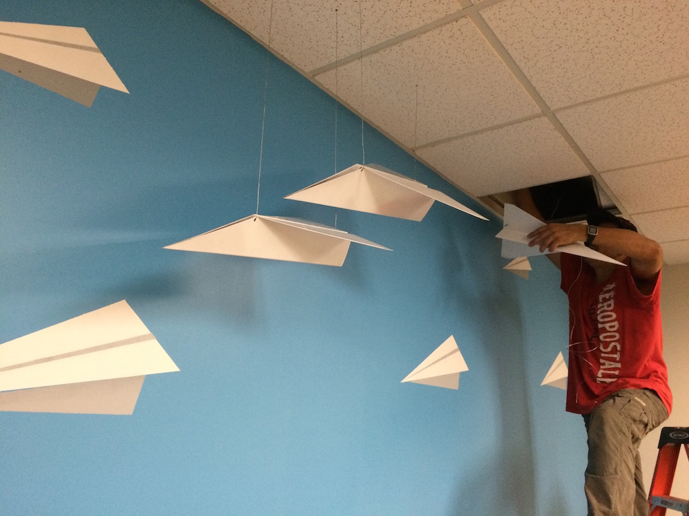 Our crew hanging folded metal airplanes from the ceiling in our customer office redesignoffice re
